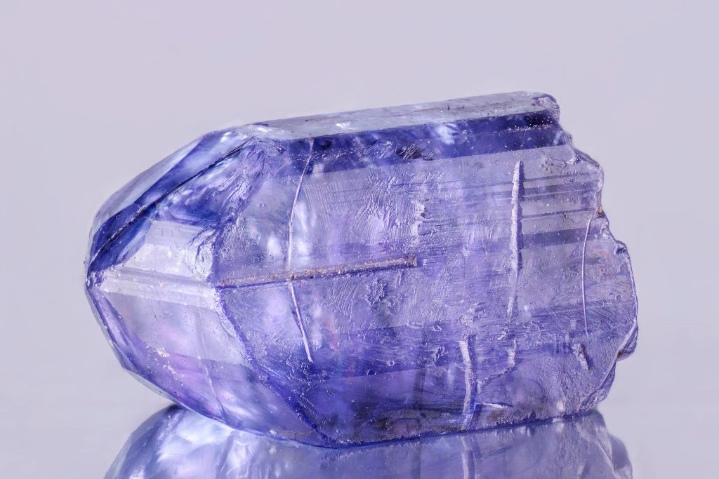 A raw tanzanite crystal on a reflective background