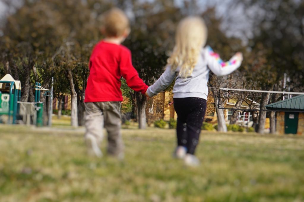 A boy and girl are holding hands in the playground