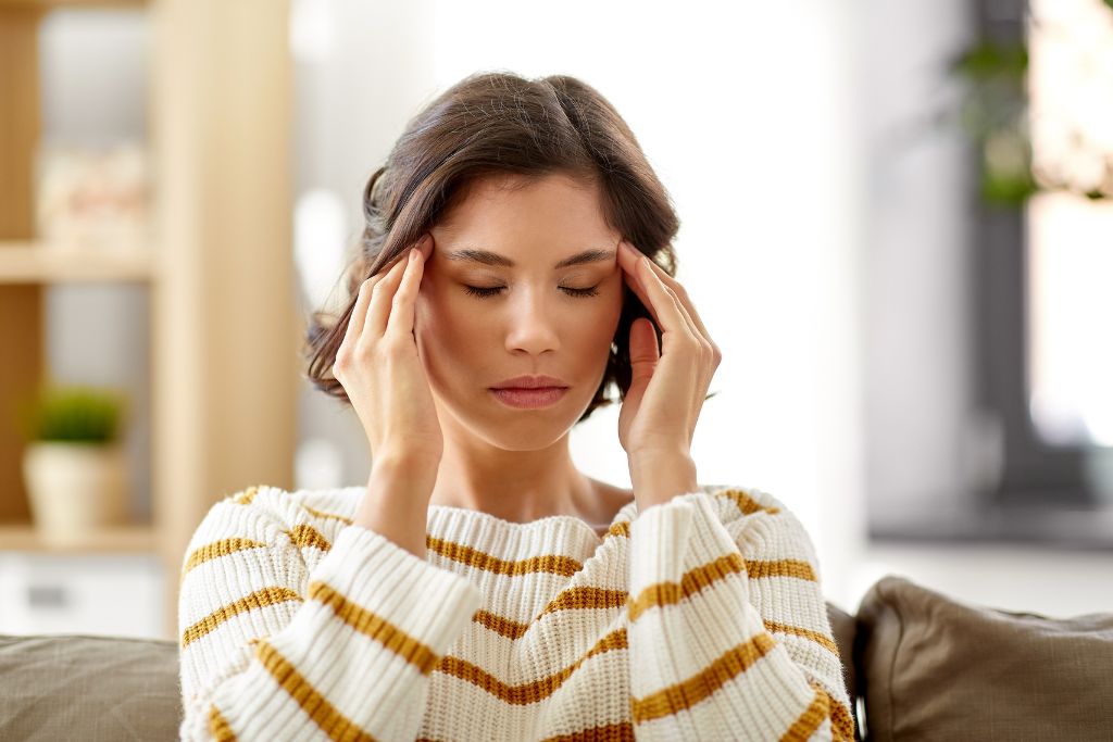 A woman with a headache massaging her temples 