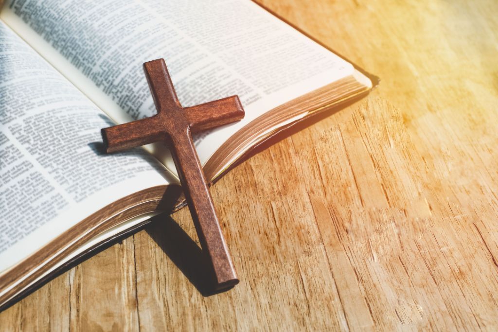 A bible and cross on a wooden table