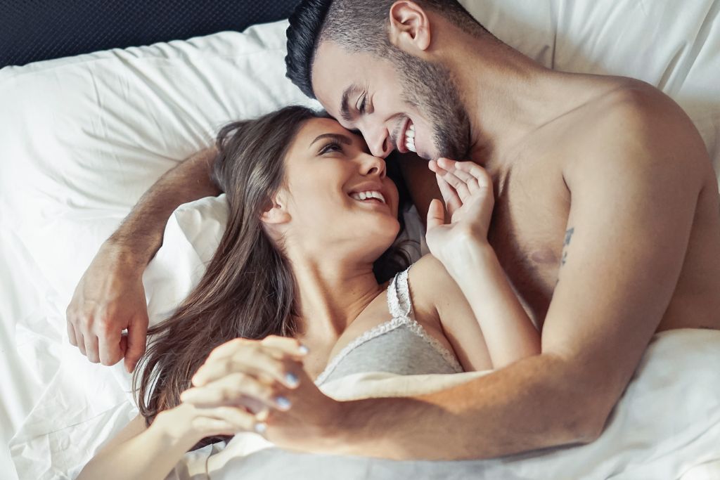 A couple is looking at each other on the bed