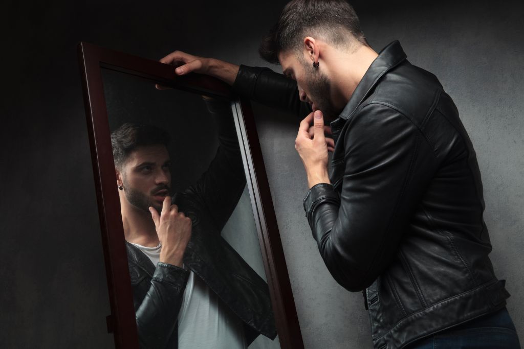 A man is looking at his reflection on the mirror