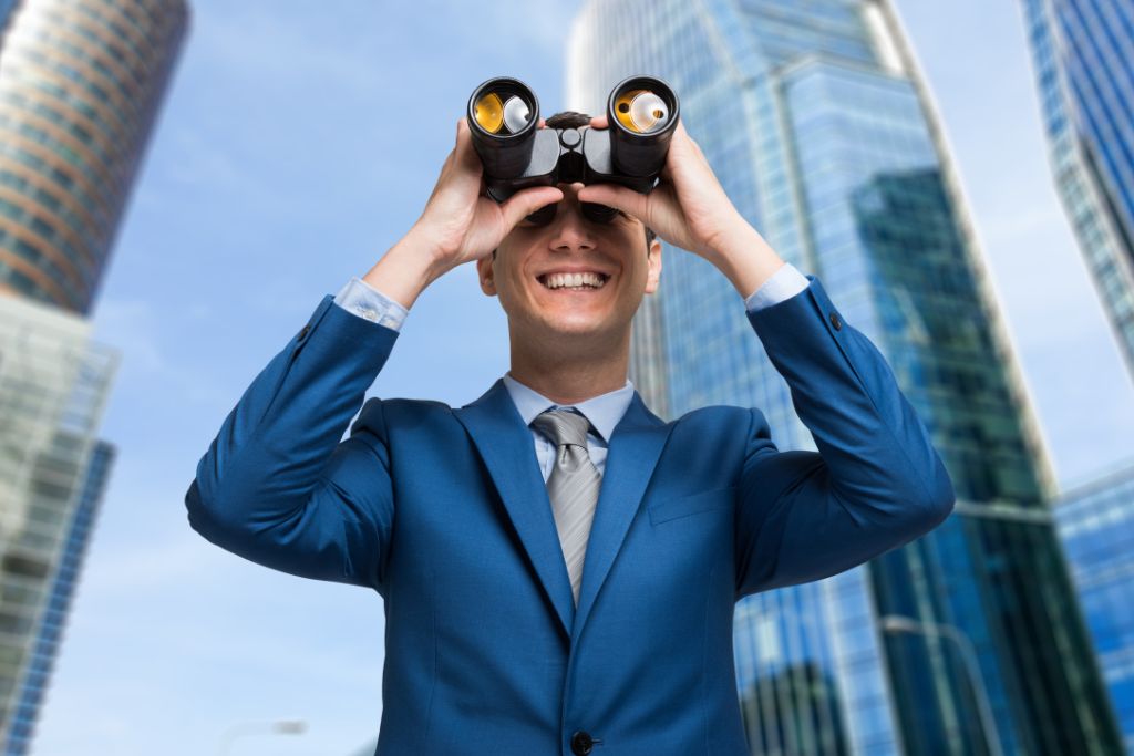 A corporate man is looking through the binoculars