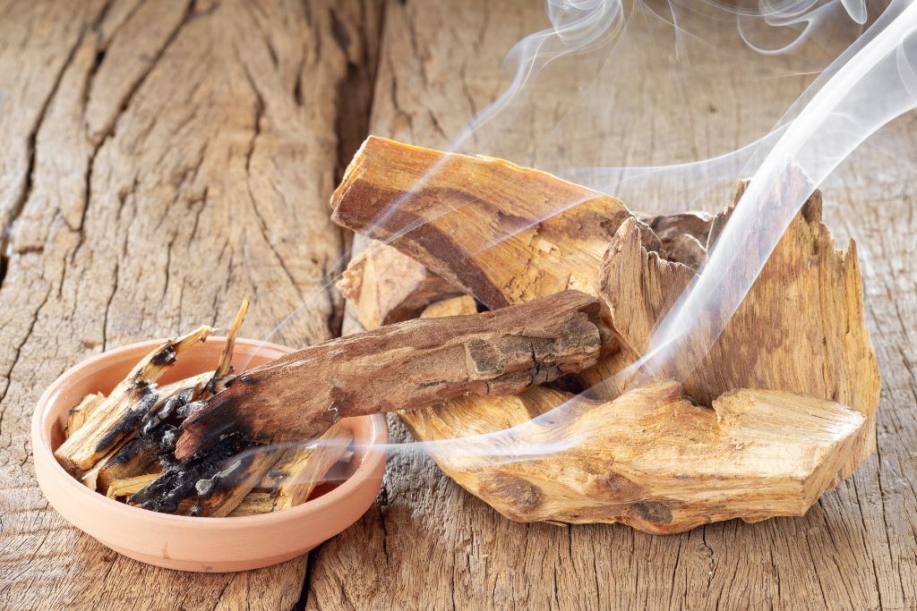 A burning palo santo on a wood and bowl