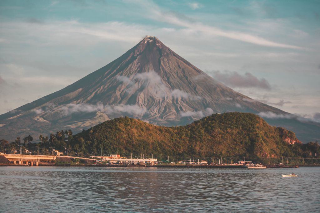 A body of water and a volcano on the background