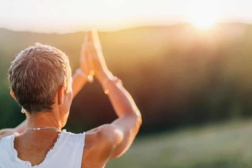 A woman meditating outside basking in afternoon sun.