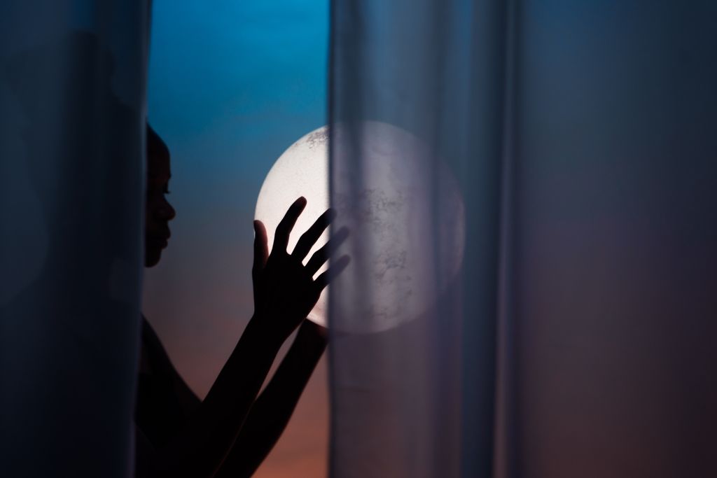 Silhouette of a woman holding a moon.