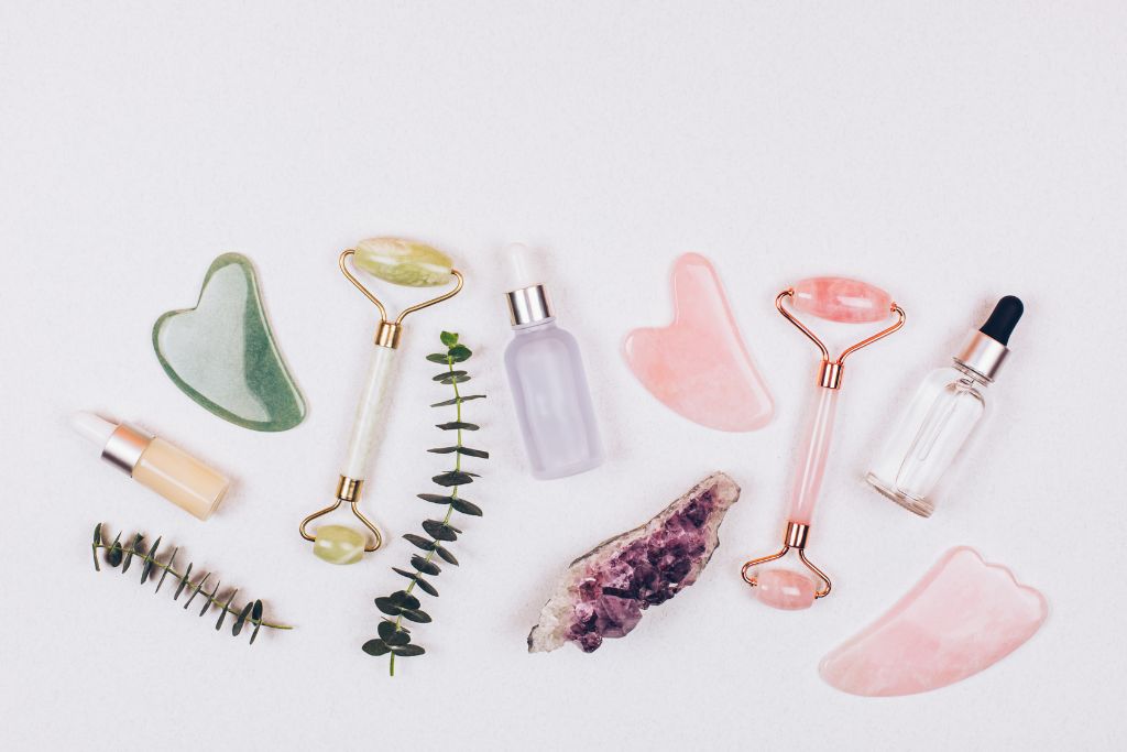 A crystal face roller and a gua sha scraper on a white background