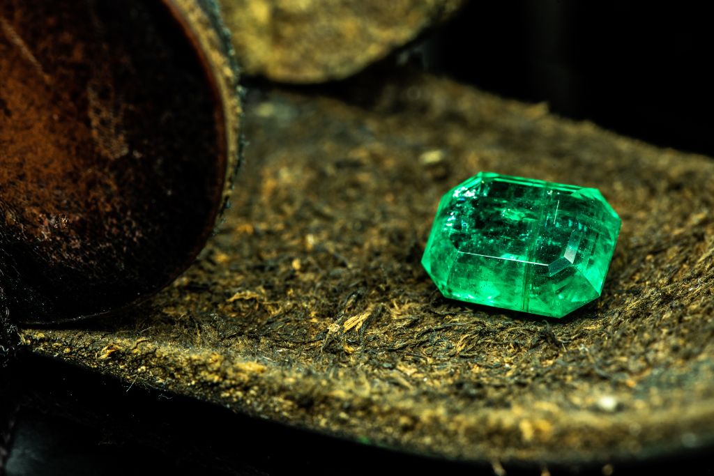 A polished emerald crystal on a cork board