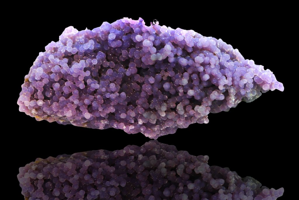 A grape agate on a black reflective background