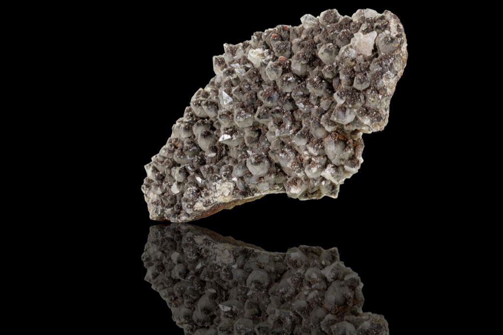 A raw Ilvaite crystal on a black reflective background