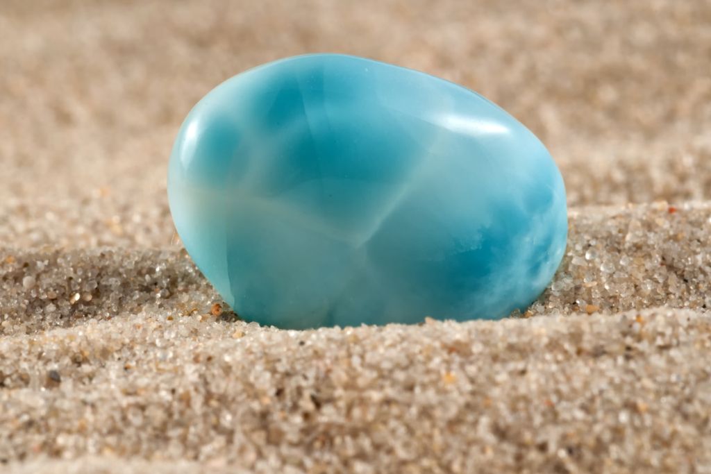 A polished larimar crystal on the sand
