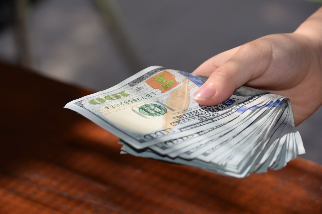 a hand holding pile of paper money bills