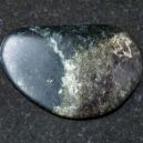 A polished Olivenite crystal on a black granite