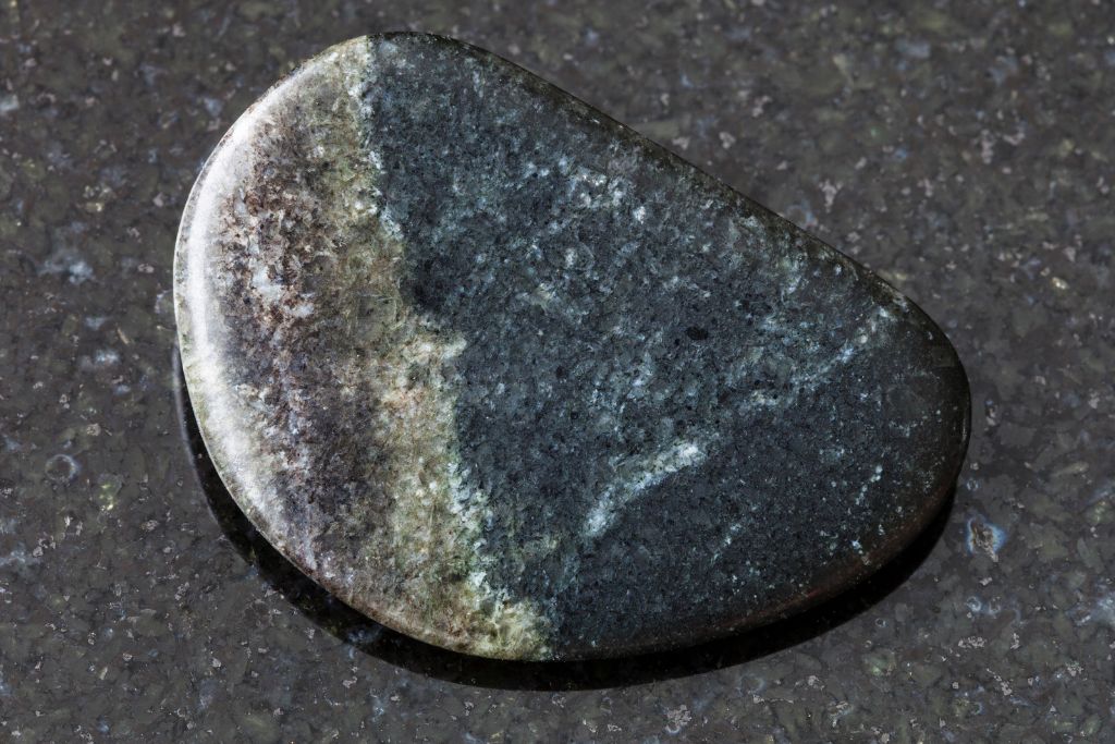 A polished Olivenite crystal on a black granite