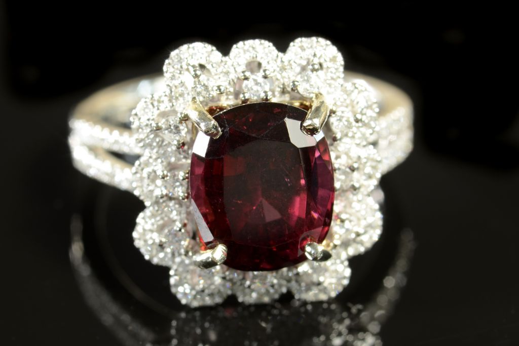 A Rhodolite ring with diamonds on a black and reflective background