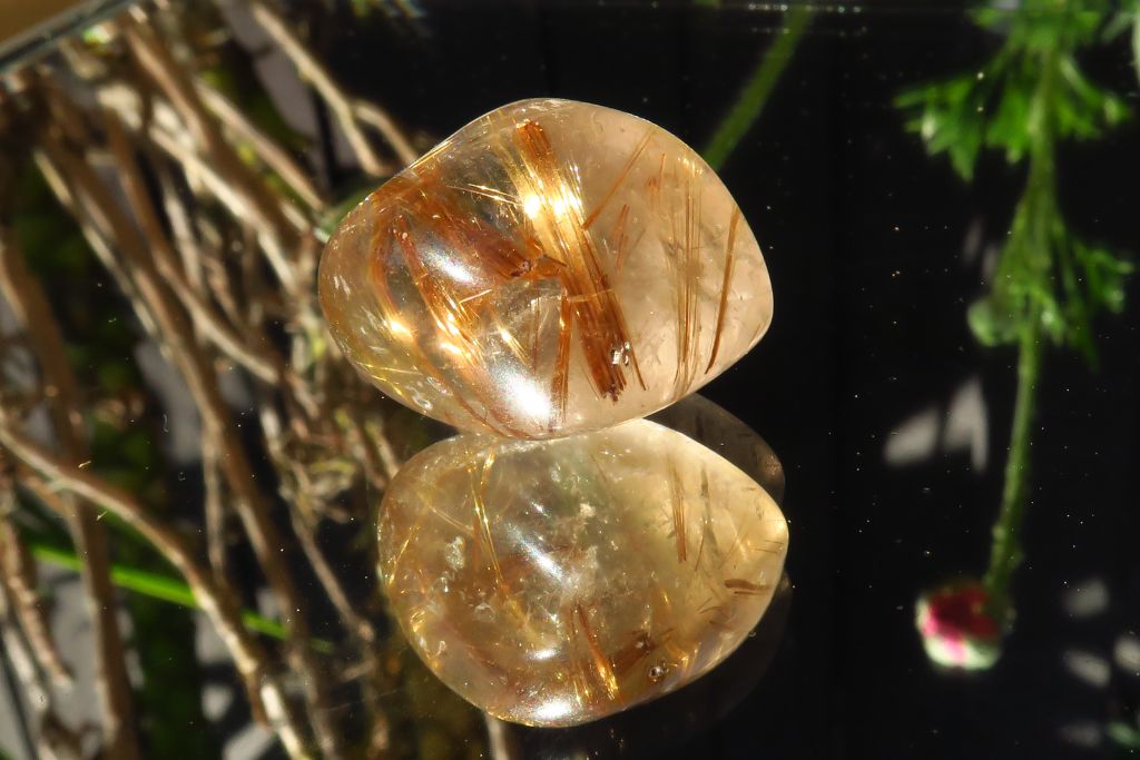 A polished Rutilated Quartz on a mirror