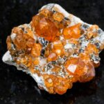 A raw Spessartite Garnet on a black granite