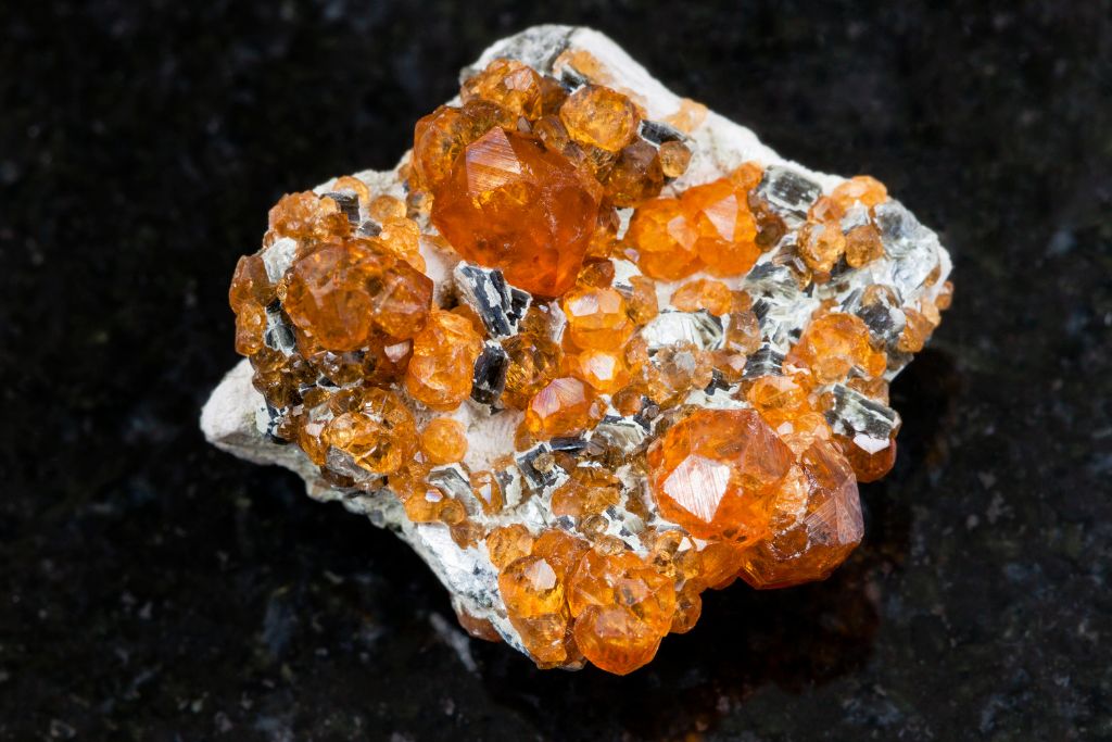 A raw Spessartite Garnet on a black granite