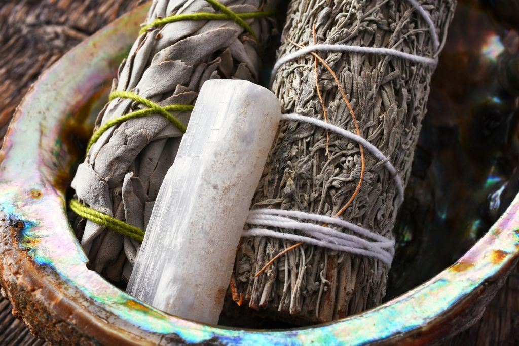 A white sage and selenite crystal on a bowl