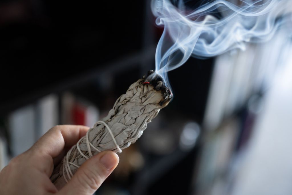 A woman cleansing the air by smudging burning sage.