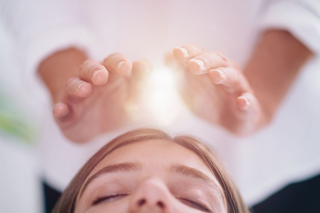 close up of a relaxed woman having reiki healing treatment