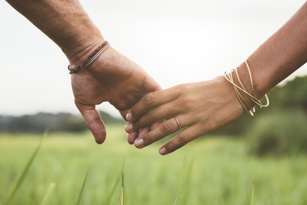 A young couple holding hands in a grass field