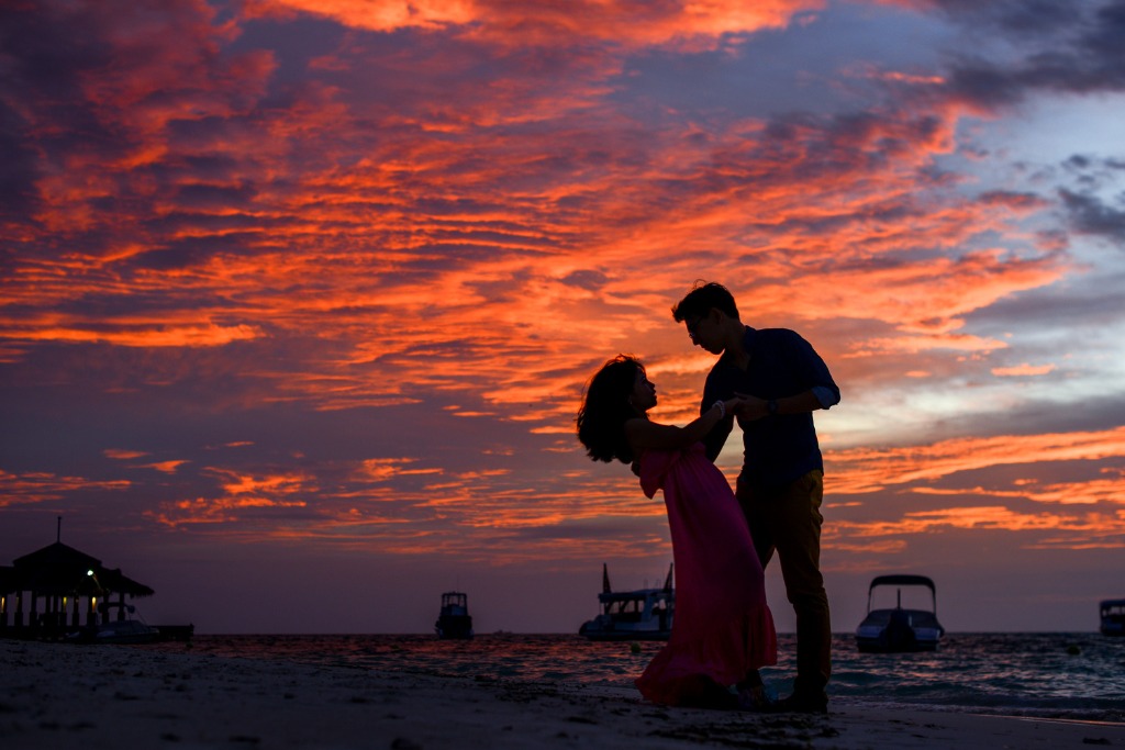 A couple holding each other at the beach at sunset