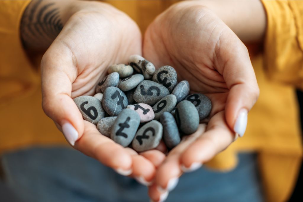 woman holding small rocks with written number on them