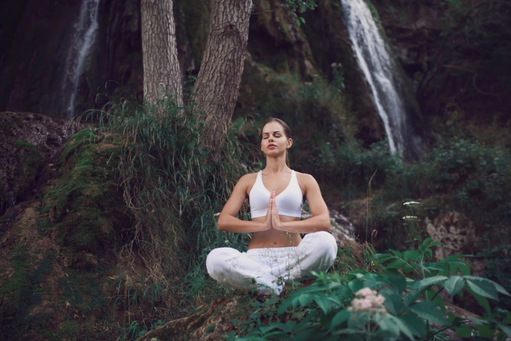 A woman meditating outdoor in the forest