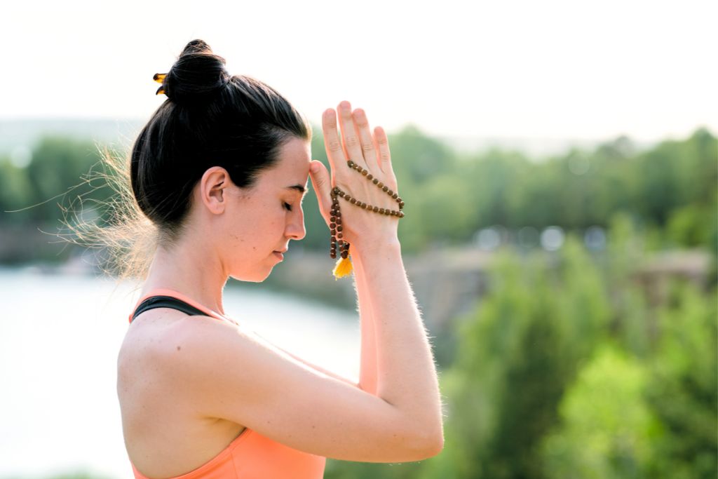 a woman praying outdoor while holding a rosary