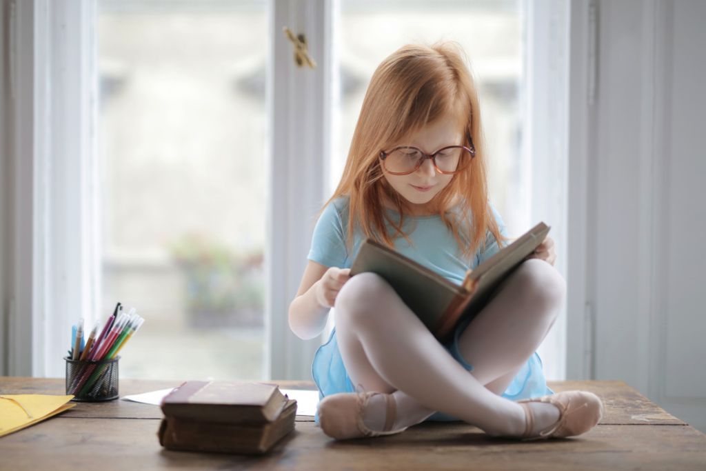 A girl is reading a book near the window