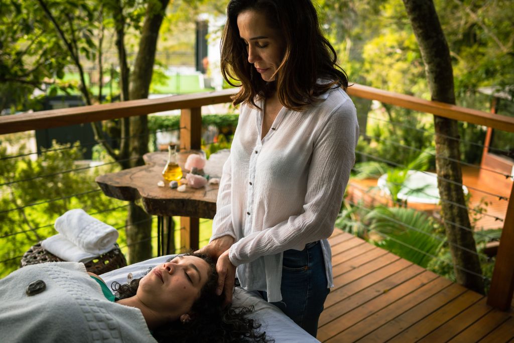 A therapist is doing reiki healing on a woman
