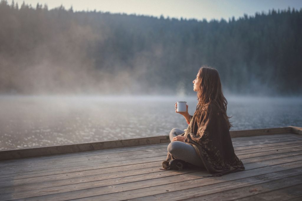 A woman is sitting on a dock in nature