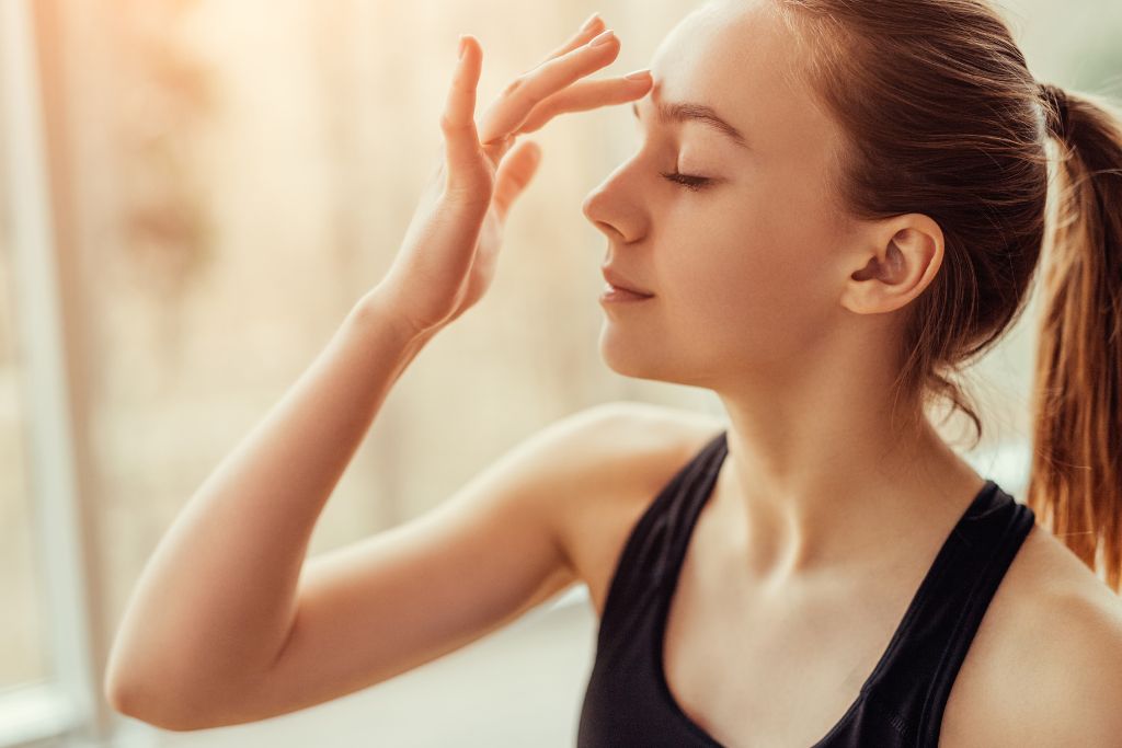 A woman is touching her third eye chakra point