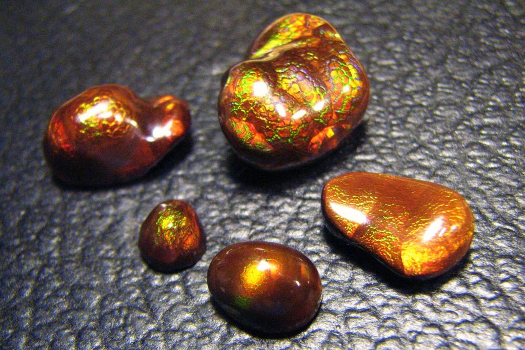 5 different sizes of Crackled Fire agate on a black leather background