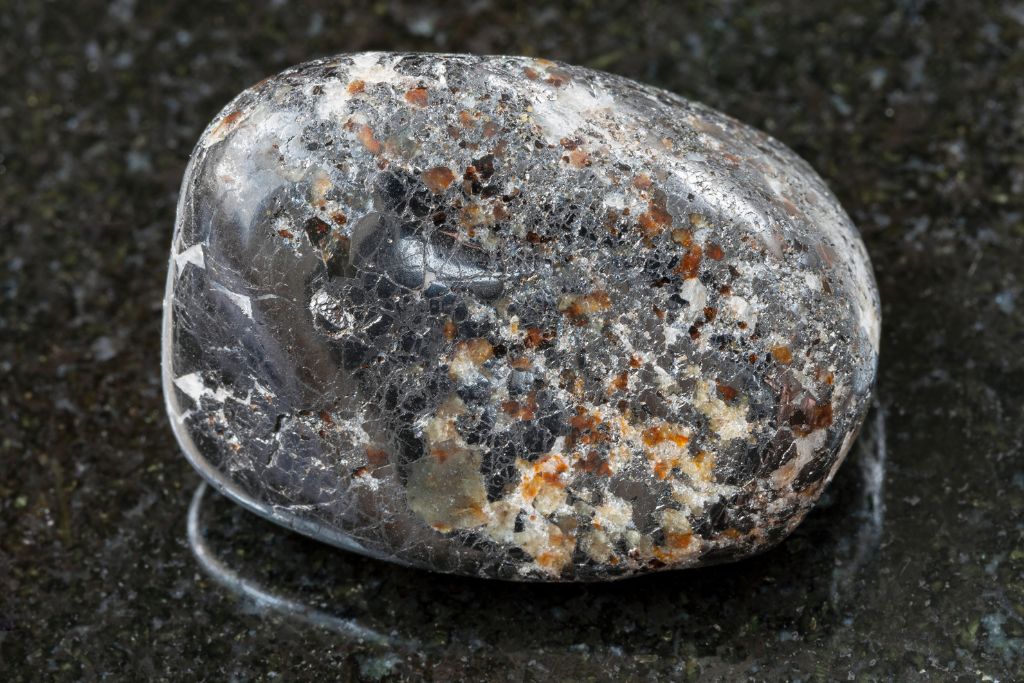 A polished magnetite crystal on a black granite