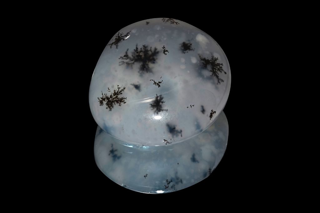 A polished Merlinite crystal on a black reflective background