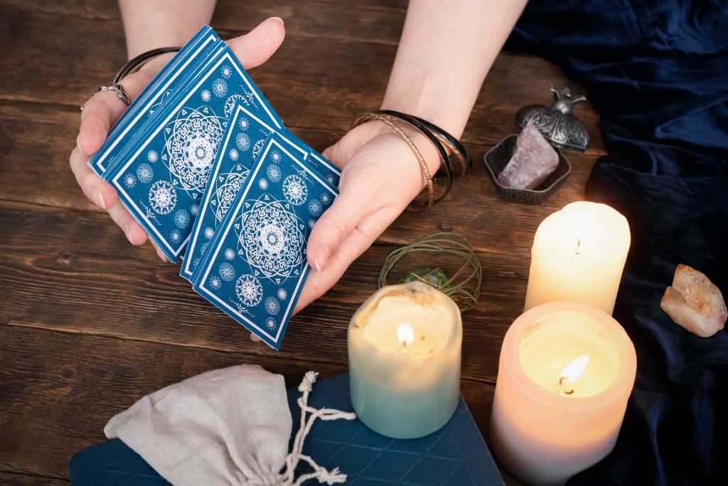 Hands holding a tarot cards surrounded by candles