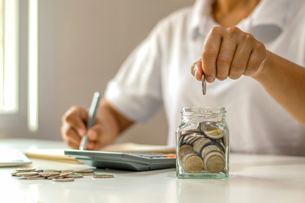 A man is putting a coin on a glass container