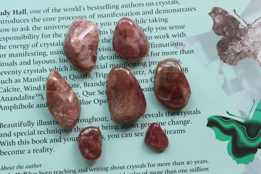 7 pieces of polished Red Aventurine in different sizes placed on top of a magazine