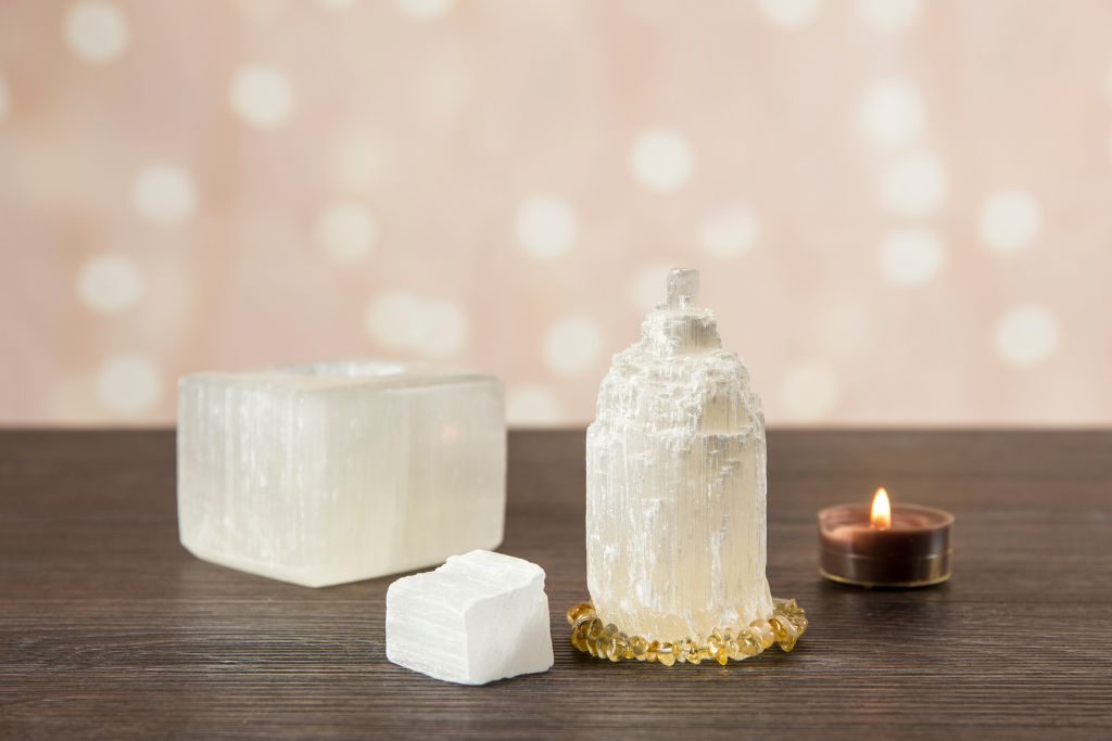 3 different sizes of Selenite placed on table with a lit candle