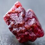 A raw spinel crystal on a blackish background