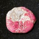 A Thulite crystal on a black granite