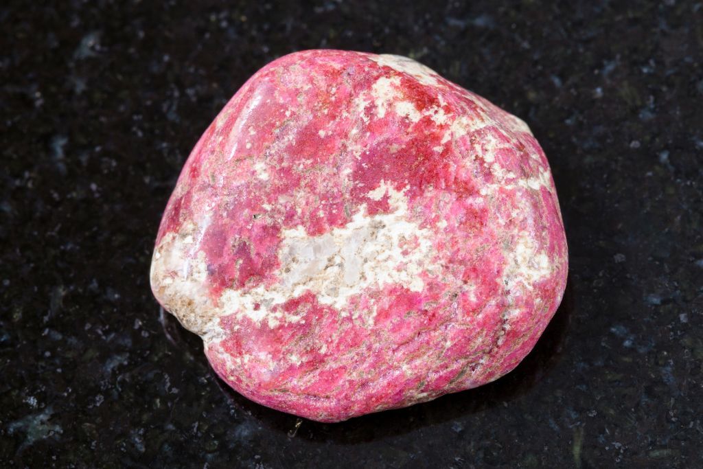 A Thulite crystal on a black granite