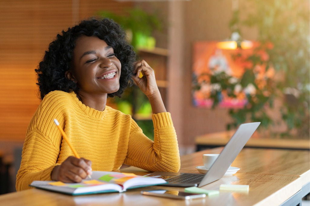 woman smiling with notebook and laptop