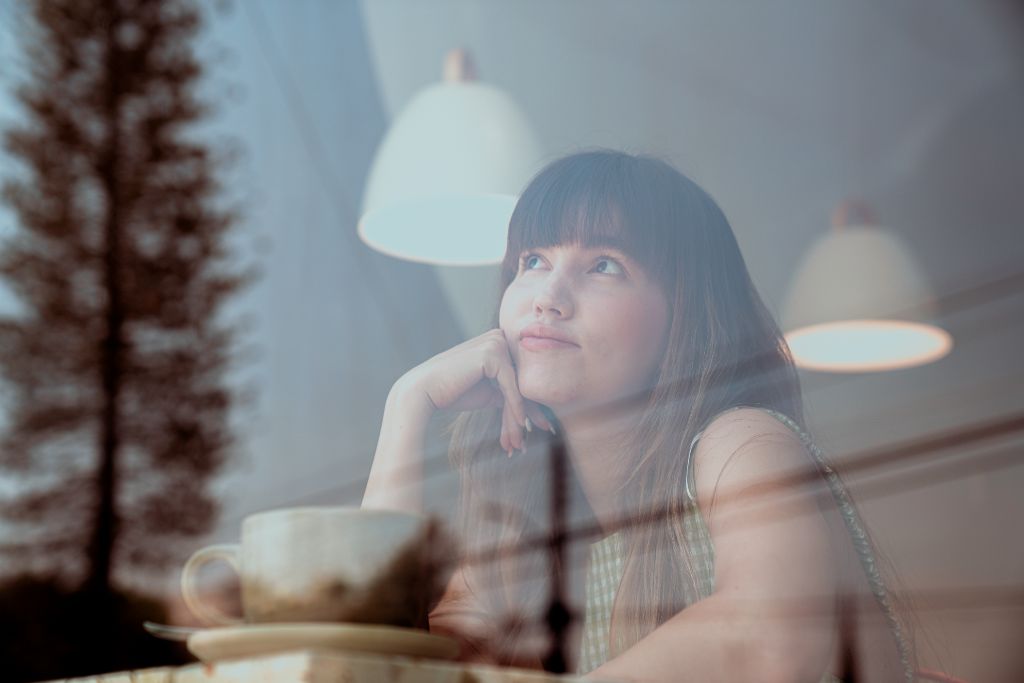 A woman is thinking while looking outside the window