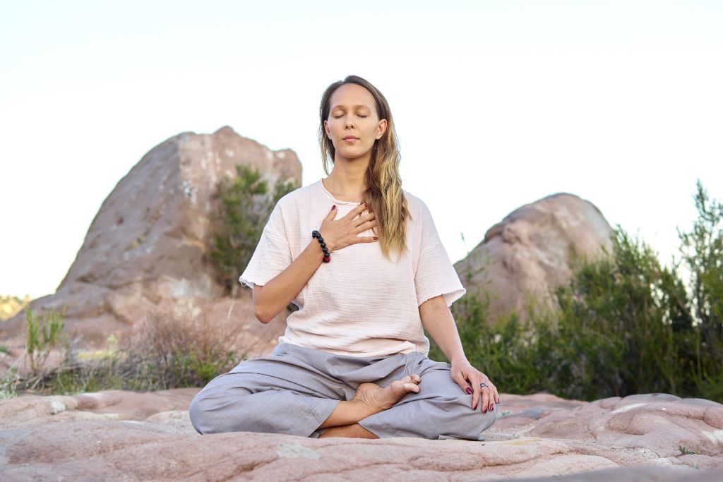 A woman is meditating on the rock