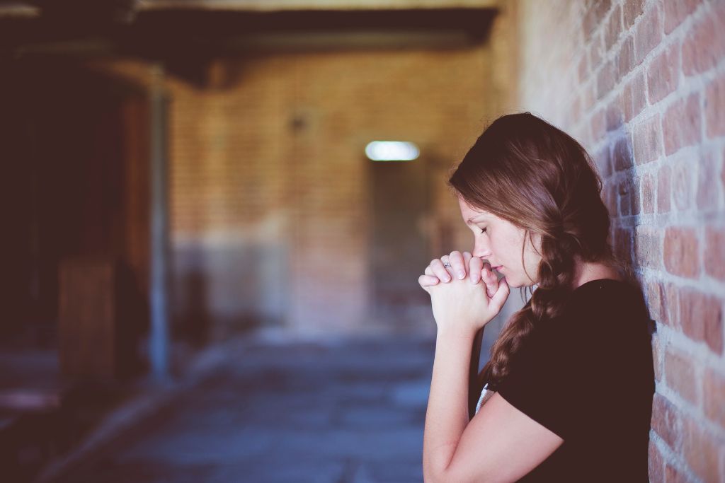 The woman is praying quietly in an empty room.