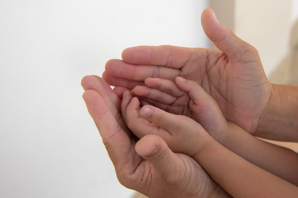 an adult hand holding a child's hand